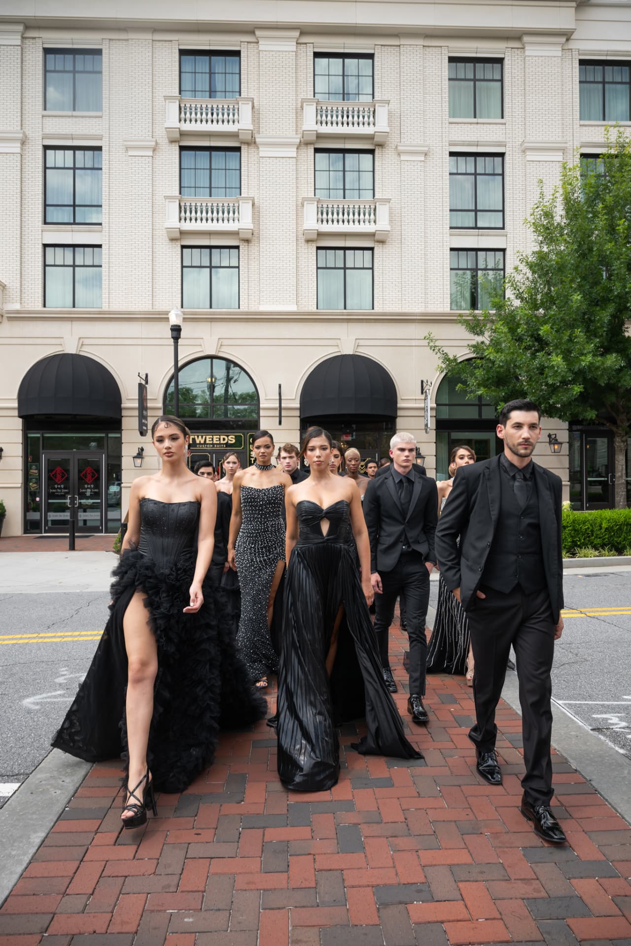 Models crossing the street in front of a limestone facade