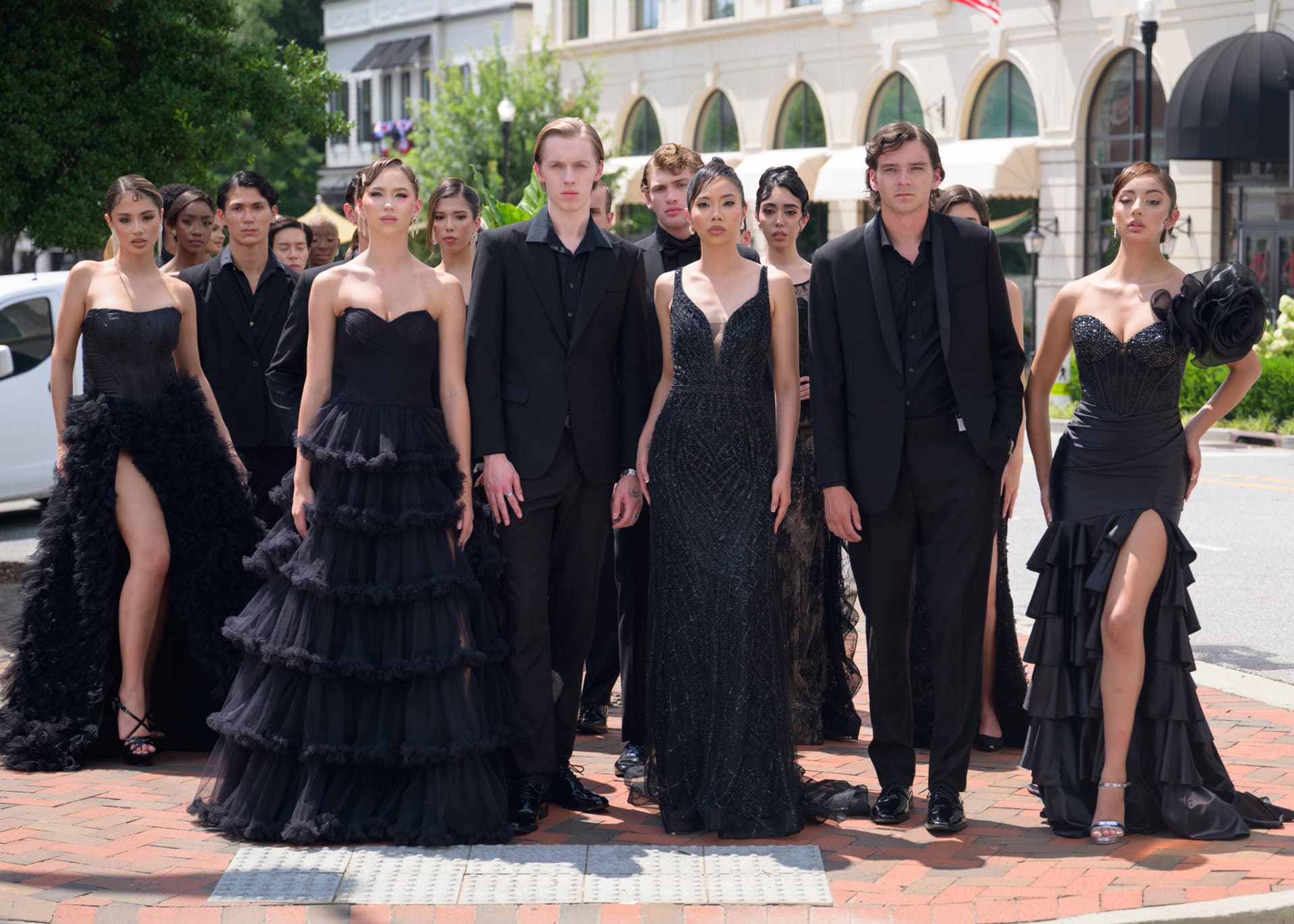 Cast standing at a street corner in full black formalwear