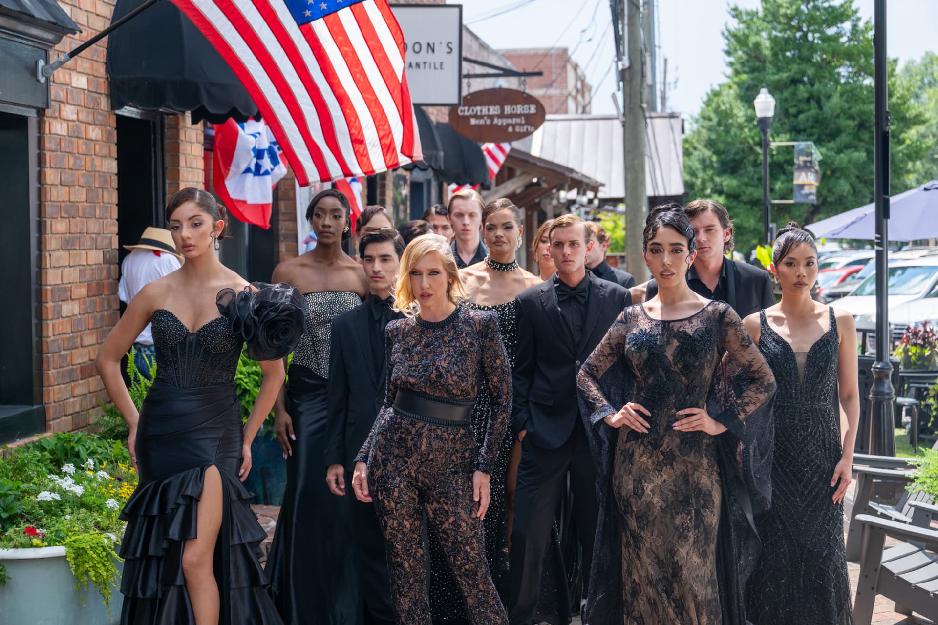 Models in black couture passing storefronts and flags