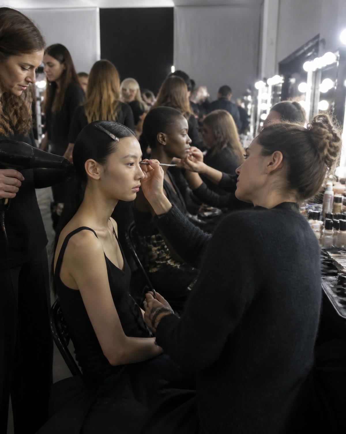 Hair and makeup artists preparing models backstage